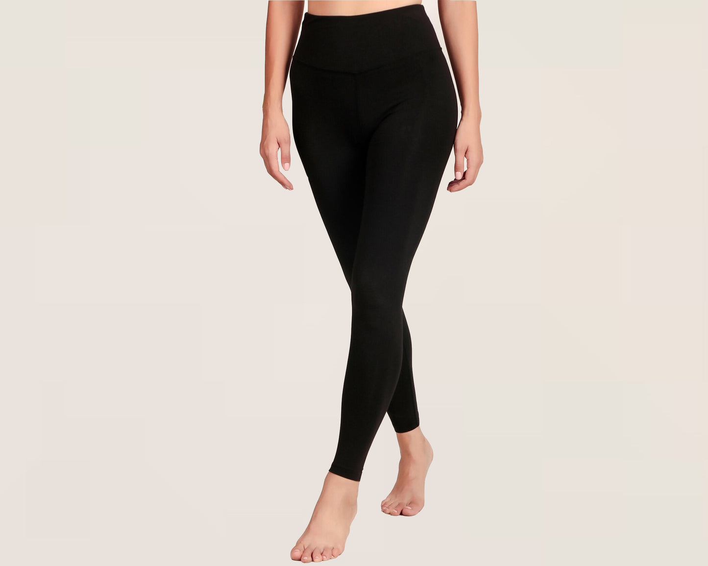 Woman wearing high-waisted black leggings against a neutral background.