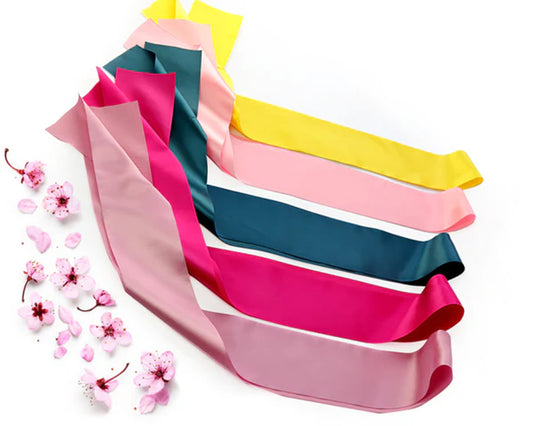 A set of satin sashes in pink, yellow, and teal, elegantly arranged with cherry blossoms on a white background.