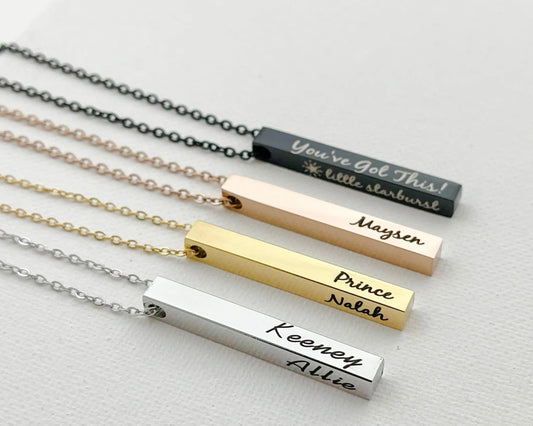 Engraved bar necklaces in black, rose gold, gold, and silver with personalized names and phrases.