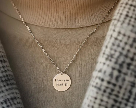 Minimalist silver disc necklace with engraved "I love you" message and date, perfect for sentimental gifts.