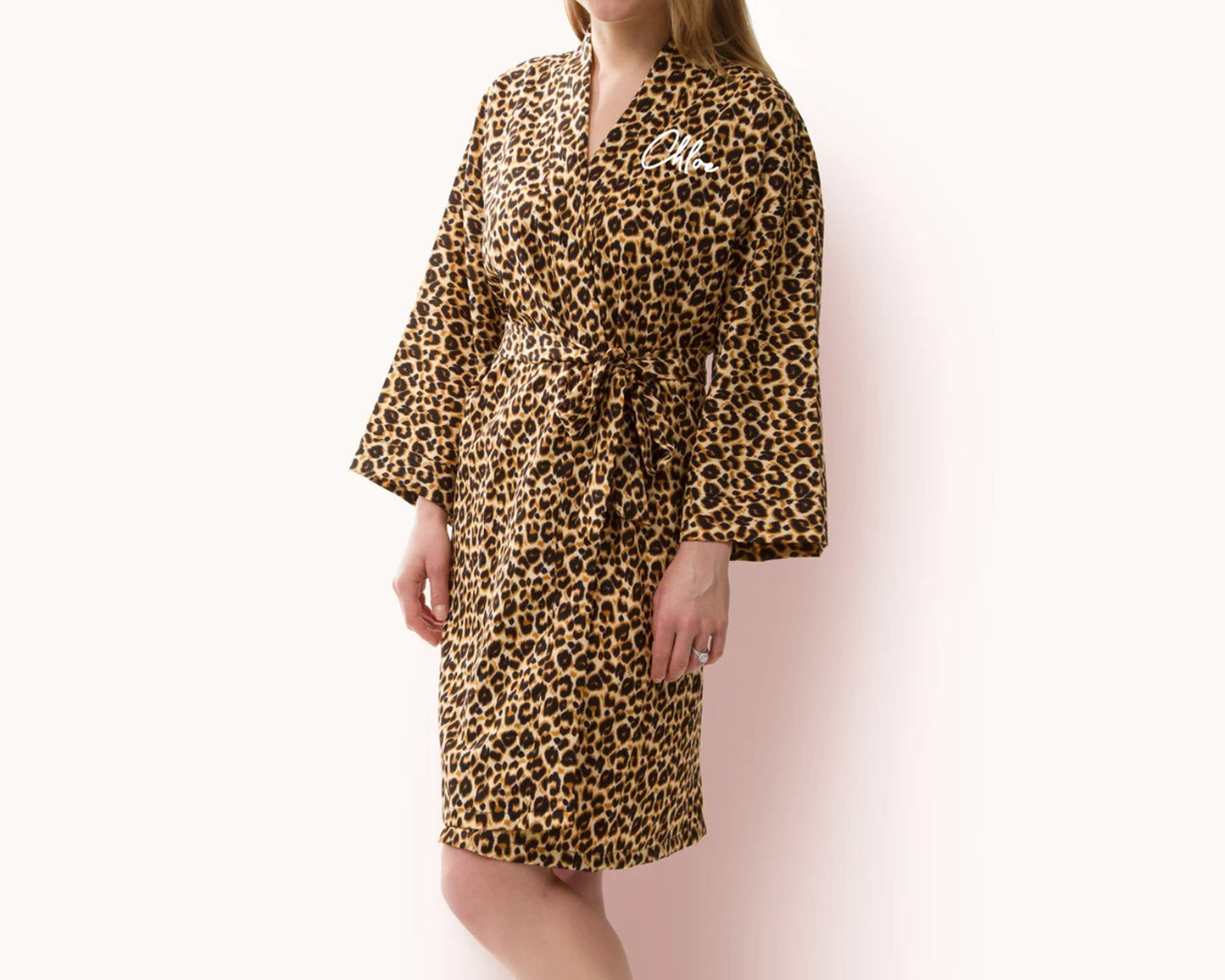 Woman wearing a brown leopard print fleece robe with a waist tie, featuring personalized white script text "Chloe" on the chest.