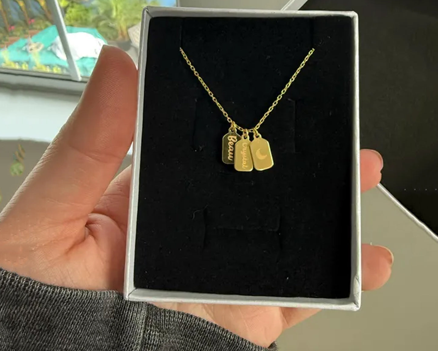 Gold name tag necklace in a gift box, featuring custom engravings.