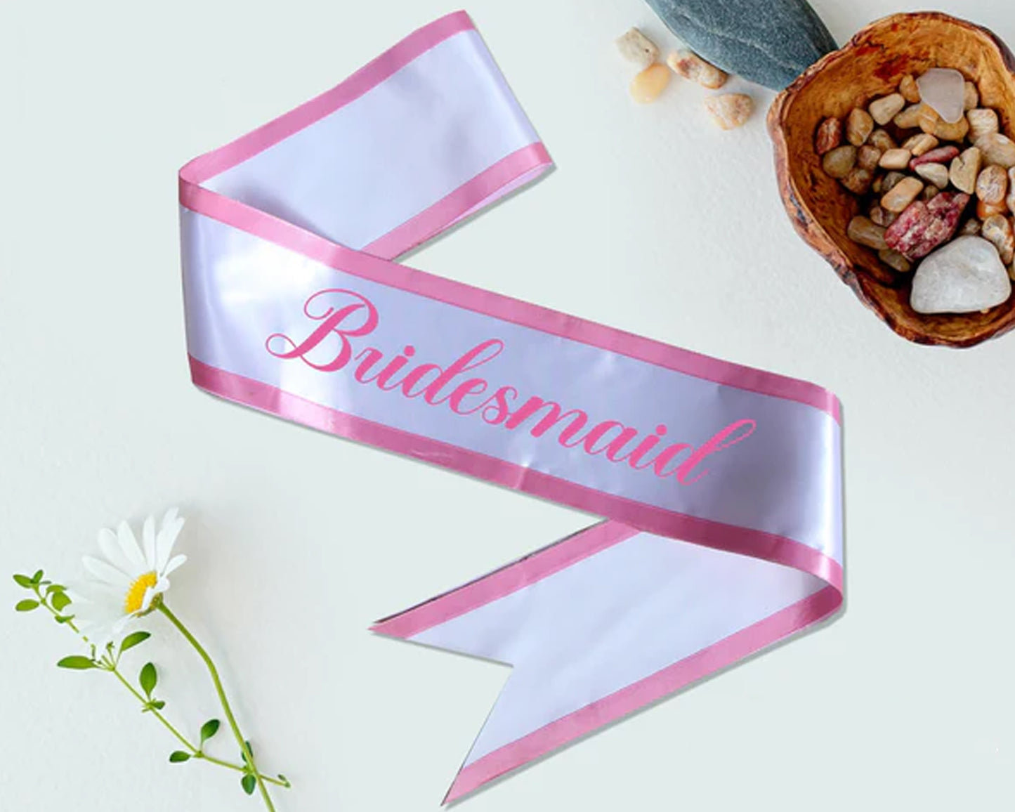 Elegant white satin sash with pink trim and "Bridesmaid" text, perfect for wedding parties and bridal celebrations.