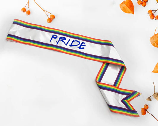 White ribbon with rainbow borders and "P.R.I.D.E" written in blue, set against a white background with orange berries.