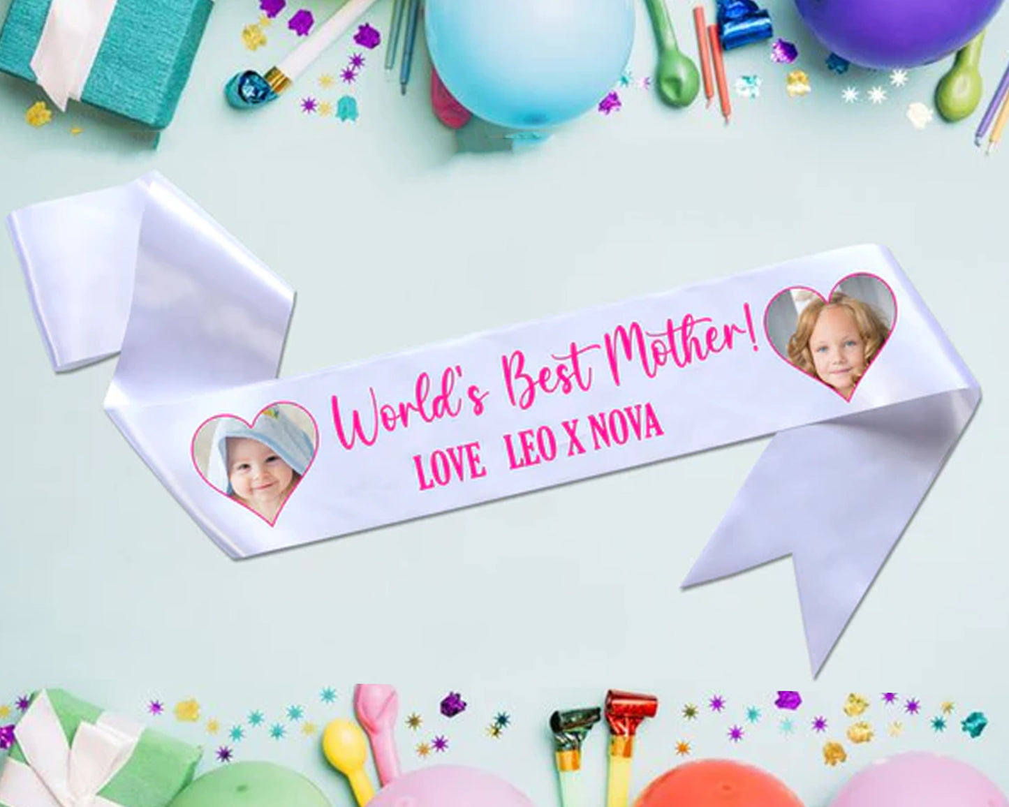 White ribbon with "World's Best Mother! Love Leo x Nova" in pink script, decorated with two heart-shaped cutouts containing children's photos.