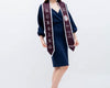 A woman in a stylish navy dress showcases a maroon and white BSN graduation sash with embroidered lettering, celebrating the Class of 2023.