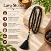 A seven chakra japa mala necklace made of black lava stones with a multicolor bead sequence, displayed on a beige stone alongside a bowl of more stones and a candle. The left side features text and icons explaining the benefits of the lava stone.