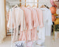 A collection of robes on a clothing rack, personalized for bridesmaids and the bride, with elegant script embroidery.