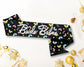 Black sash with colorful butterfly and floral patterns, featuring "Bride Babes" written in elegant white script.