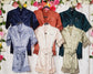  A collection of satin bridesmaid and flower girl robes in various colors, featuring delicate lace trim and embroidered text, displayed against a floral backdrop.