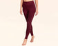 Woman wearing high-waisted burgundy leggings, walking barefoot against a neutral background.
