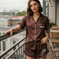 Brunette model wearing chocolate brown satin ruffle set with Emma name and cheer logo