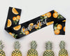 A black satin sash featuring vibrant orange slices and blossoms, customizable text, and a tropical pineapple backdrop.