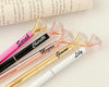 A stylish set of personalized pens with diamond-shaped tops in pink, black, rose gold, gold, and white, engraved with different names.