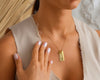 A woman showcasing a delicate gold chain with personalized name bars and a heart charm, elegantly resting on her chest.