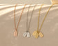 Three delicate tag necklaces in rose gold, silver, and gold with engraved names, displayed on a soft beige surface.