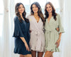 Three women wearing stylish ruffle robes in navy, beige, and sage green, perfect for bridesmaids, lounging, or special occasions.
