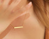 Elegant gold bar necklace with a personalized engraving, delicately worn by a woman with soft lighting.