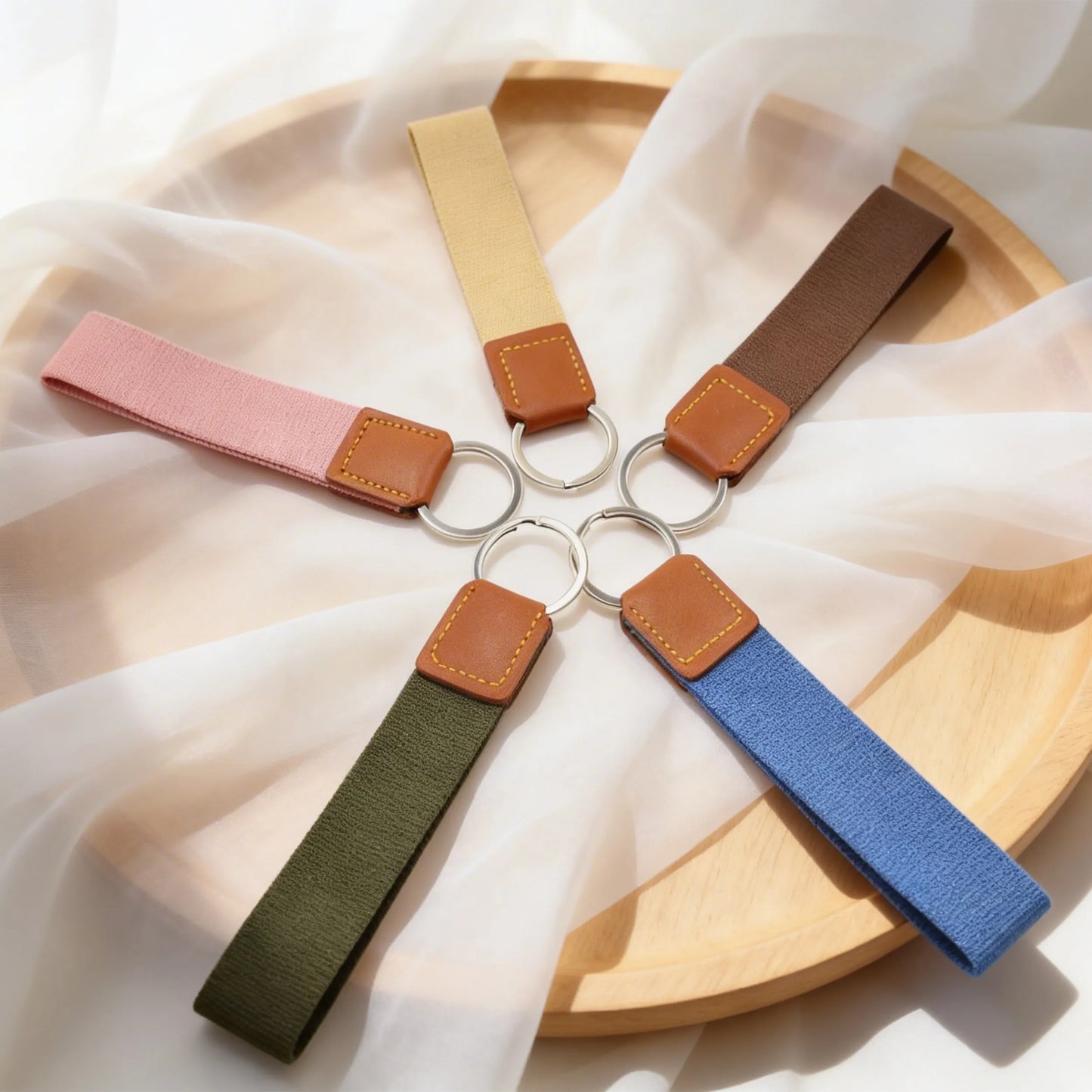 Five keychains with fabric straps on a wooden surface