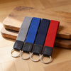 Four keychains with different colored straps on a wooden surface