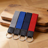 Four keychains with different colored straps on a wooden surface