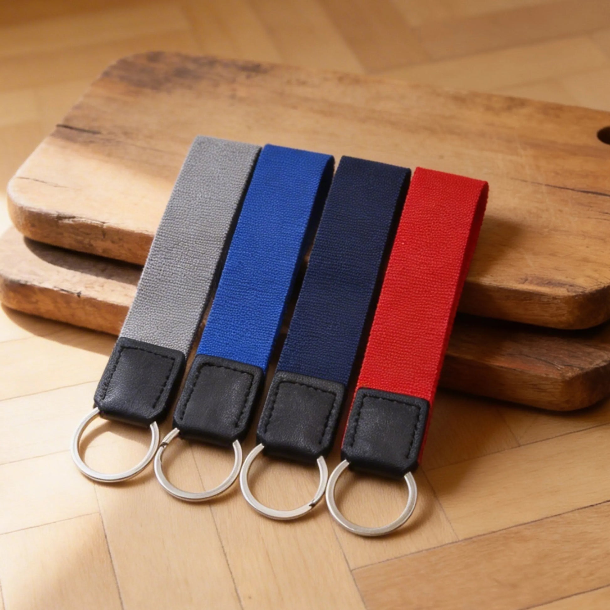 Four keychains with different colored straps on a wooden surface