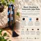 A black and orange beaded mala necklace with a tassel is draped over a rock on a wooden surface, with a branded promotional graphic behind it reading 'MACK Elevate Your Energy' and 'Black Obsidian & Amazonite Japa Mala 108 Beads.'.