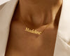 Gold nameplate necklace with "Madeline" in cursive on a delicate chain.