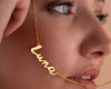 Close-up of a woman holding a gold name necklace that spells "Luna," highlighting its elegant cursive design.