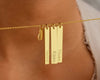 A personalized gold bar necklace with multiple engraved name pendants, elegantly displayed on a woman's neck.