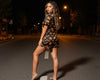 Woman in a Halloween-themed dress standing on a dark street at night.