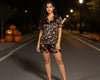 Woman wearing a Halloween-themed pajama set on a street at night with pumpkins.