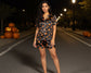 Woman wearing a Halloween-themed pajama set on a street at night with pumpkins.