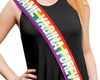  A person wearing an LGBT-colored sash with bold white text over a black sleeveless outfit.