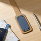 Leather luggage tag with blue accent on a wooden surface with passport and map.