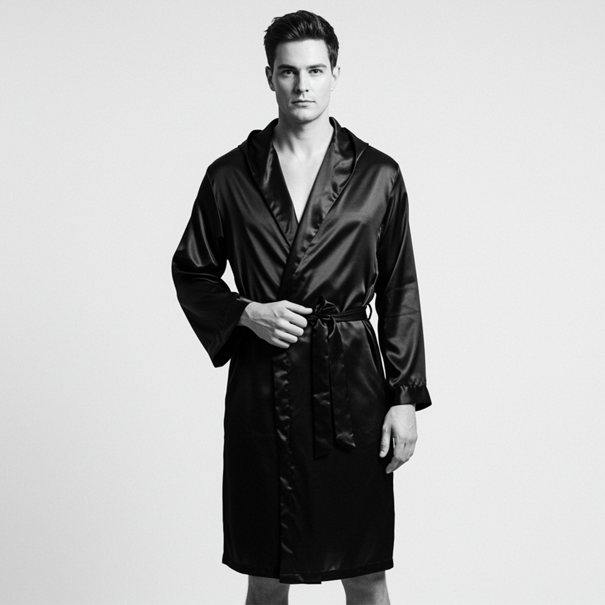Man wearing a black satin robe on a light gray background