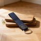 Navy blue keychain strap with a metal ring on a wooden surface