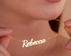 Close-up of a woman delicately holding a custom gold necklace featuring the name "Rebecca" in an elegant script design.