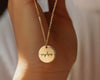 Close-up of a gold round pendant necklace engraved with the name "Sophia," hanging from a delicate chain.