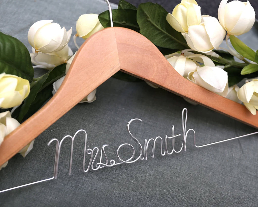 Wooden hanger with "Mrs. Smith" in silver wire, surrounded by white roses.