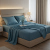 Soft pastel blue satin sheet set on a classic tufted bed with fresh roses