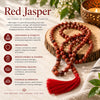A red jasper beaded prayer necklace with a red tassel draped over a rustic wood slice, set on a textured cream fabric beside a lit candle. The left side features informational text and icons about the benefits of red jasper.