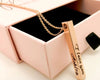 A rose gold pendant necklace engraved with a loving message, displayed with a pink gift box.
