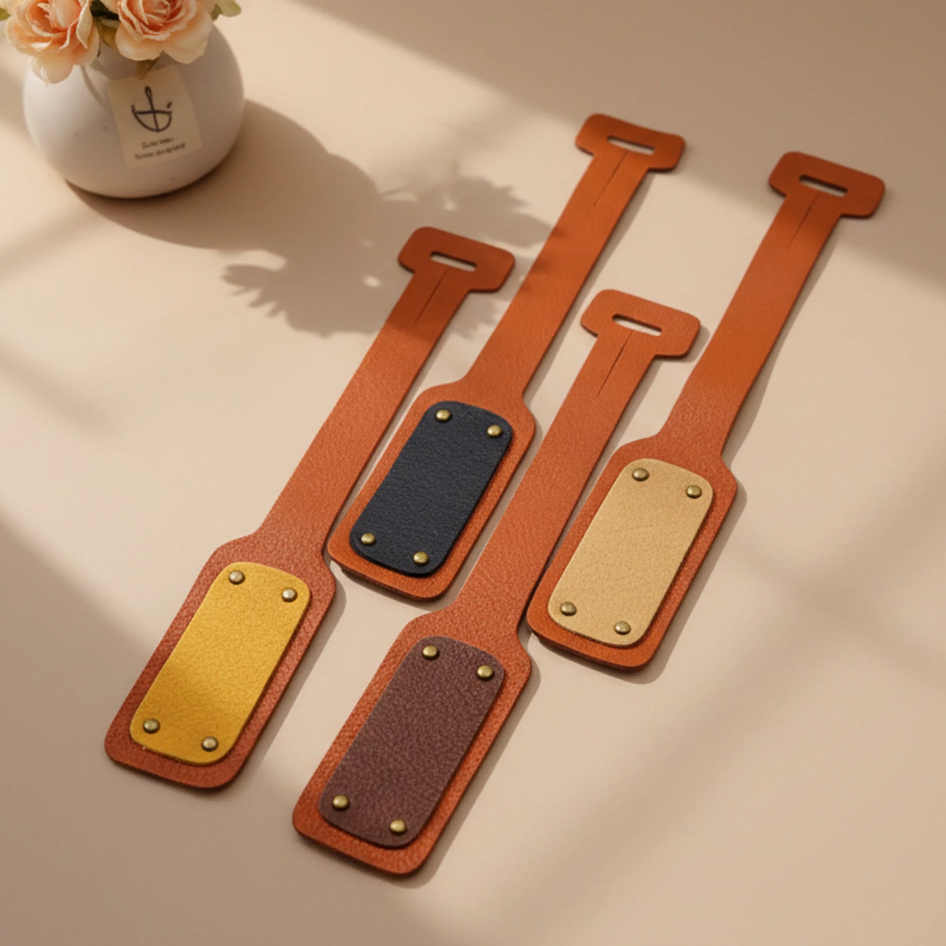 Set of brown leather straps with metal buckles on a beige surface.