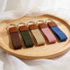 Set of five keychains with brown leather ends on a wooden tray