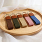 Set of five keychains with brown leather ends on a wooden tray