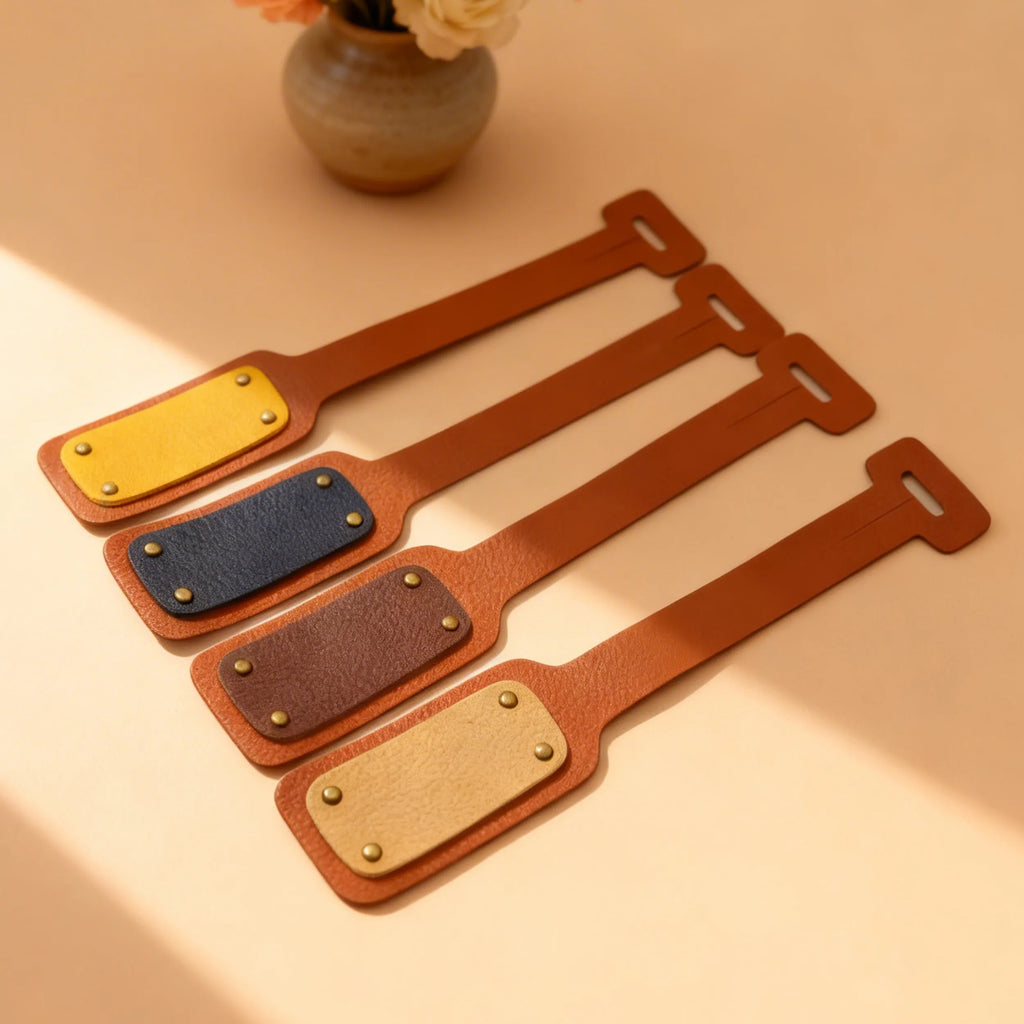 Set of leather luggage tags in various colors on a beige surface with a vase in the background.
