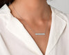 Stylish silver bar necklace with a custom engraved name, elegantly worn over a white pajama 