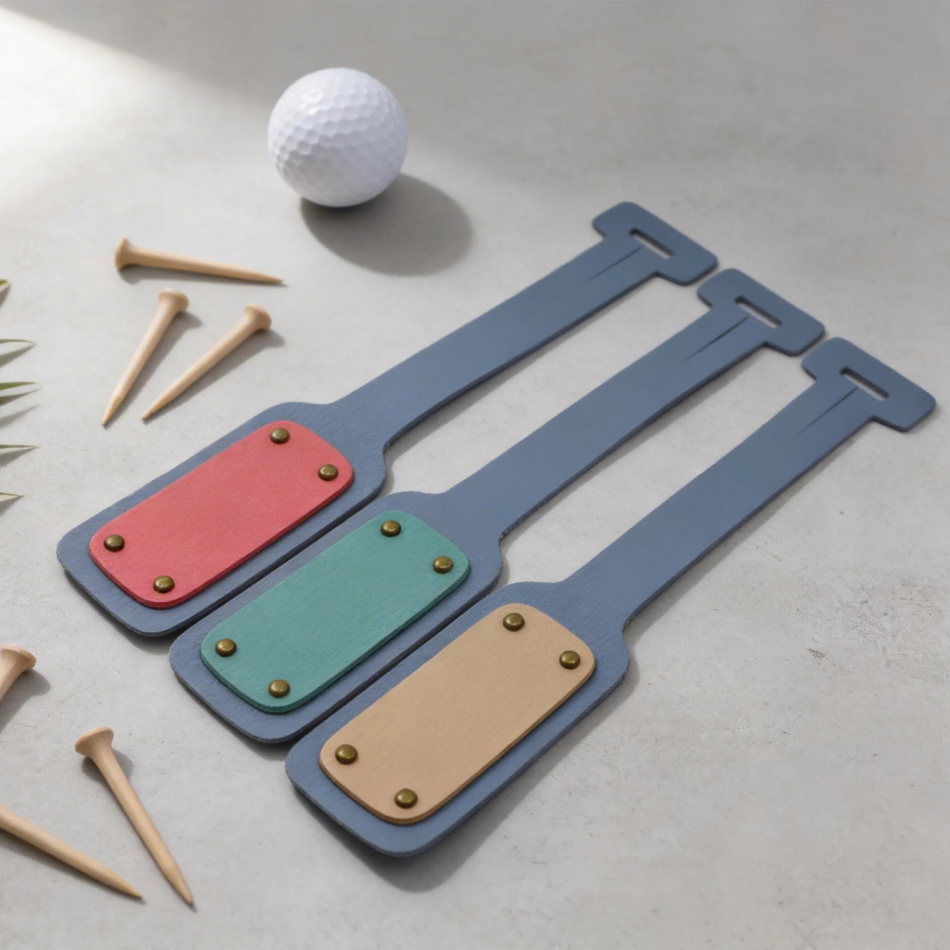 Three colorful BAG TAGS on a light surface with a golf ball and tees.