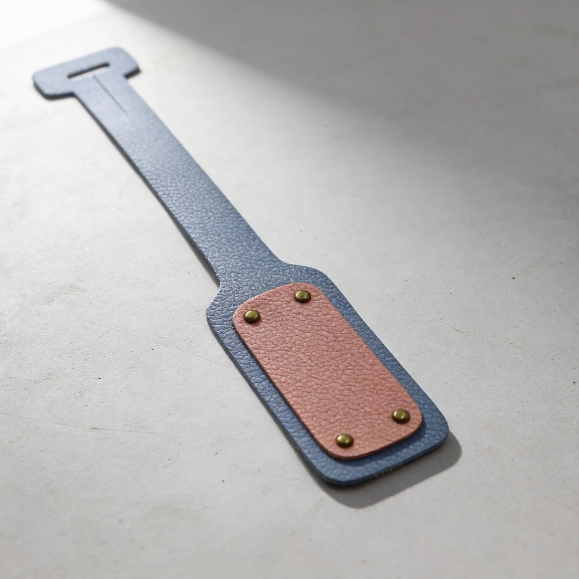 Two-tone leather strap with metal clasps on a light gray background